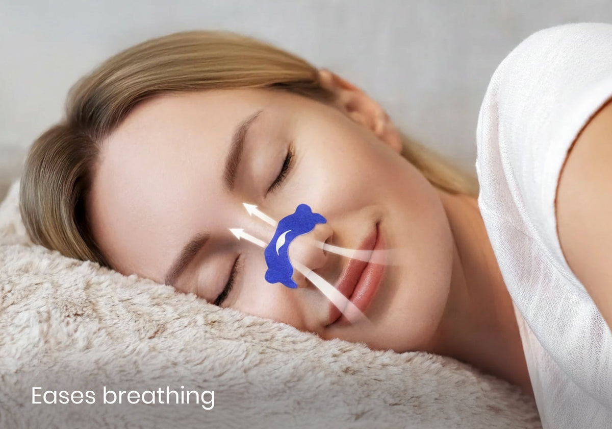 Close-up of a sleeping woman wearing a blue Manta nasal strip with white airflow graphic arrows and text reading "Eases breathing".