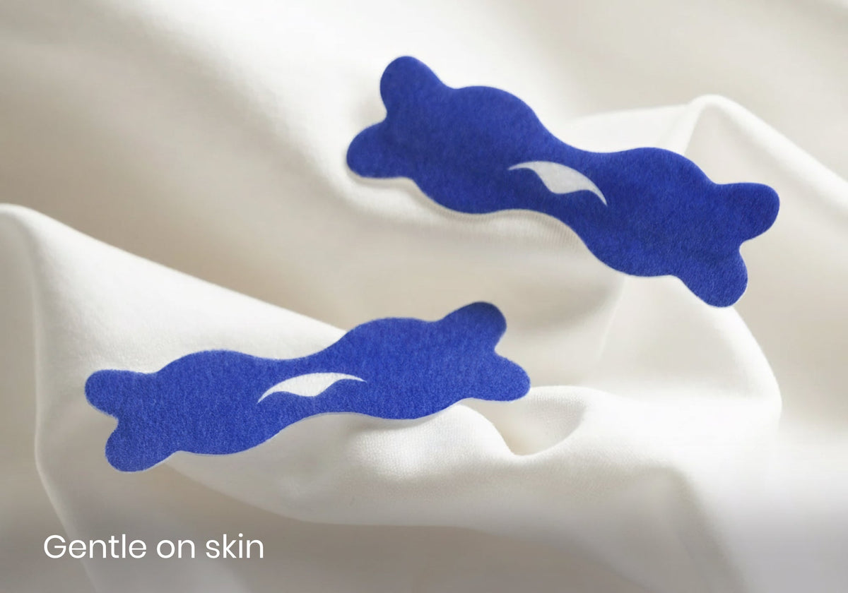 Two dark blue Manta nasal strips featuring the Manta Sleep logo resting on soft white fabric with overlay text reading "Gentle on skin".